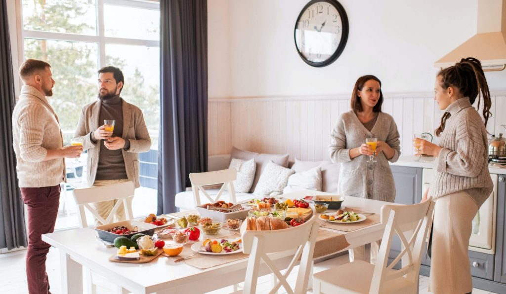 a group of people standing around a table with food on it