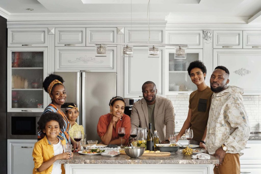 a group of people standing around a kitchen table